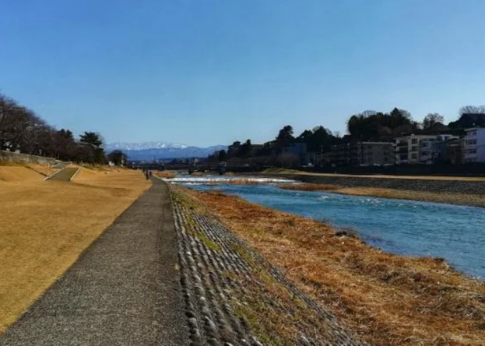 A picture taken in Kanazawa, showing the river and the banks running alongside stretching into the distance.
